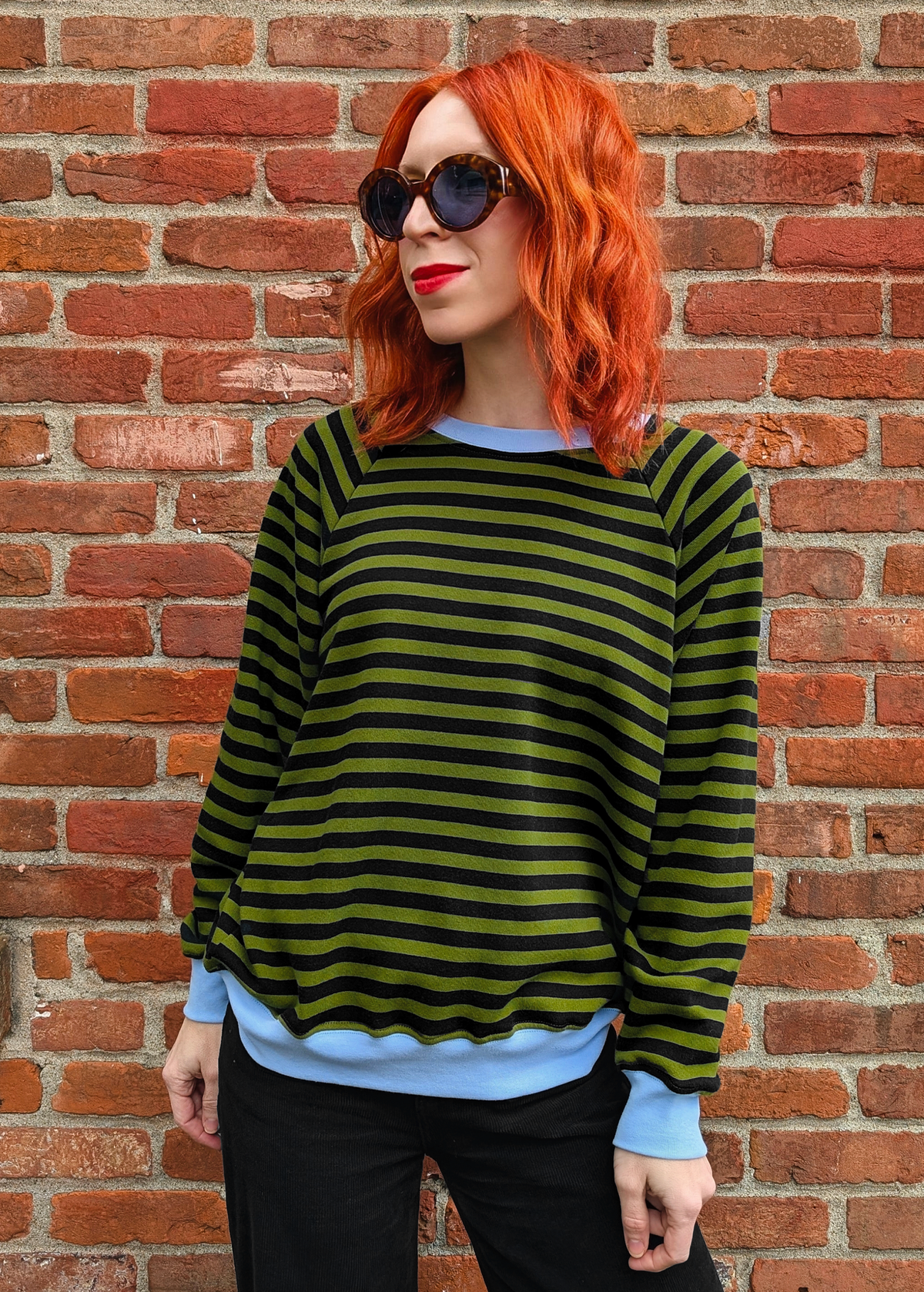 Olive green and black stripe raglan crew neck sweatshirt with ribbed sky blue cuffs, collar, and hem. Slouchy, relaxed fit. Made of 100% french Terry cotton